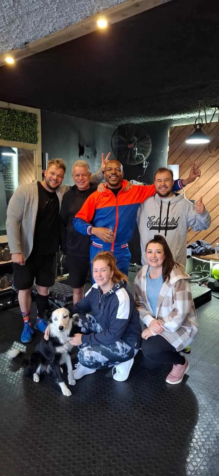 A group of XO Fit clients, men and women, with the gym dog