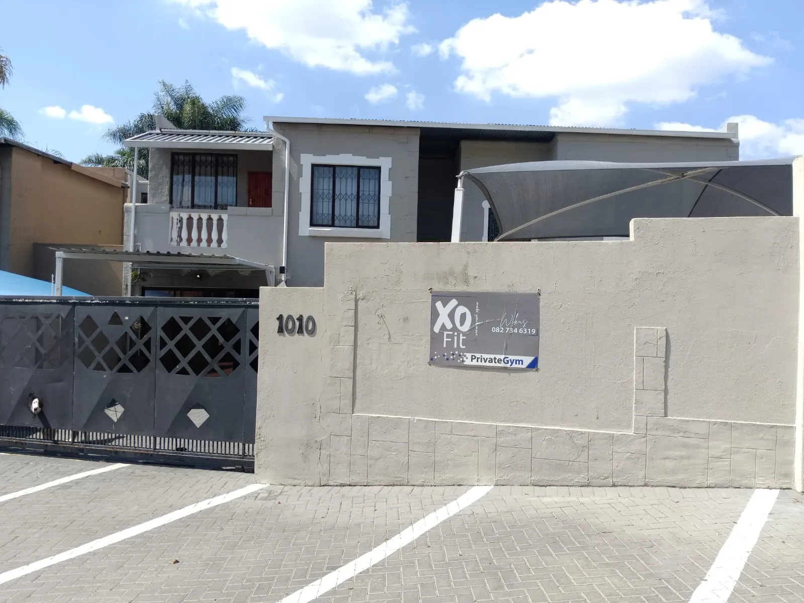 The street entrance of the XO Fit private gym: number 1010 on the wall, the XO Fit sign beside it and the marked parking bays in front