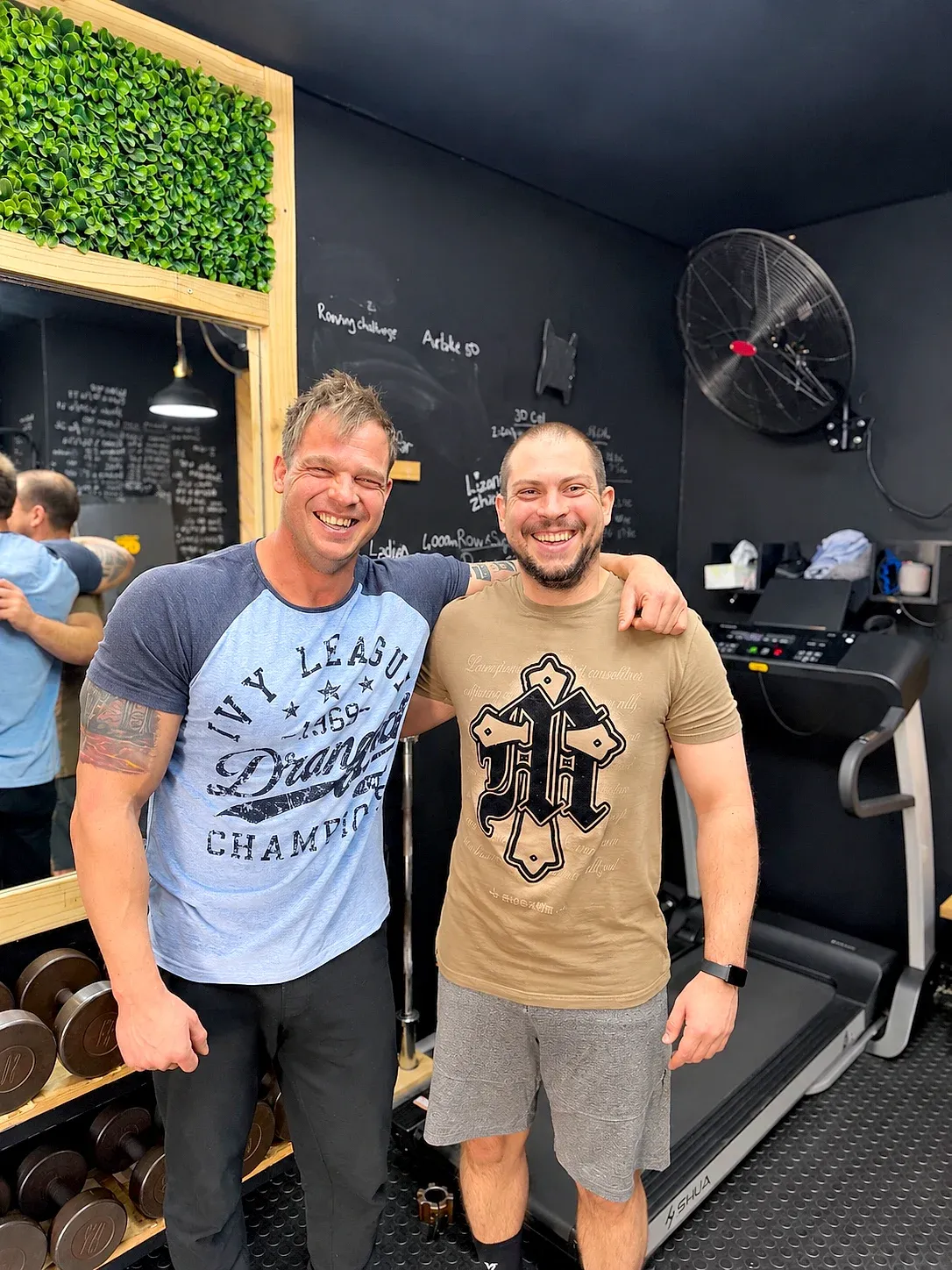 Wikus, on the left in a blue and navy T-shirt, with a client in the XO Fit gym