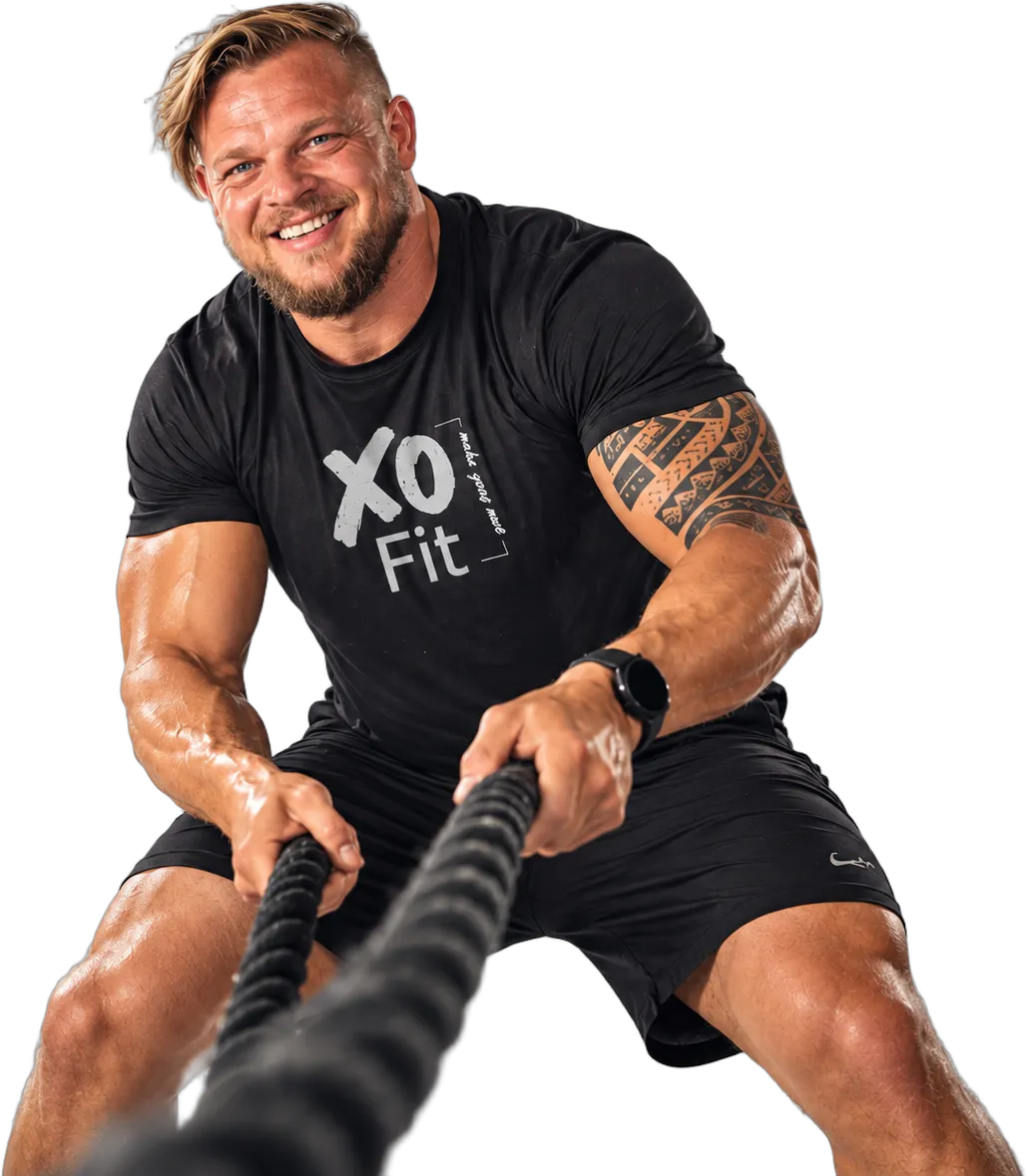 Wikus van Dyk, pulling battle ropes and smiling, wearing an XO Fit shirt