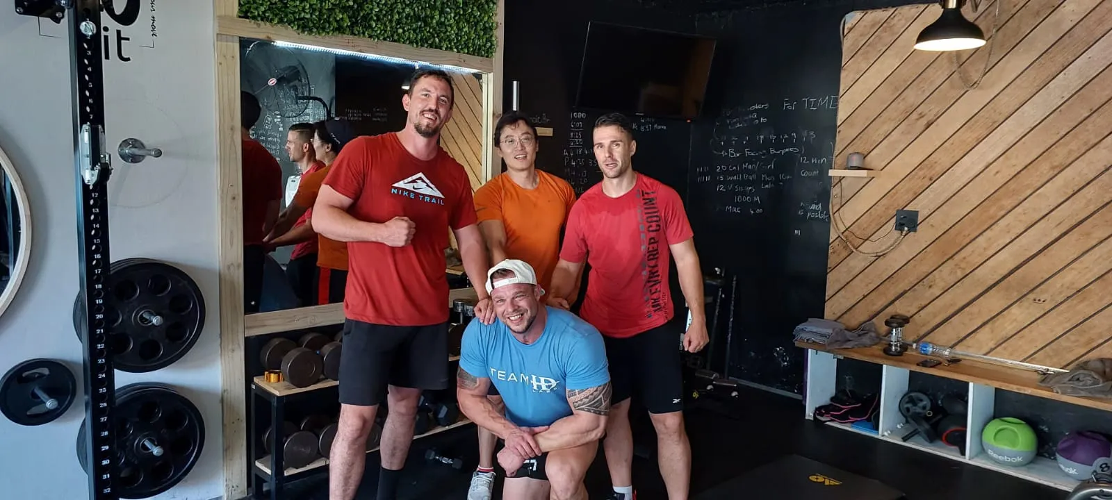 Wikus with clients in the XO Fit gym, in front of the chalkboard and the plate rack